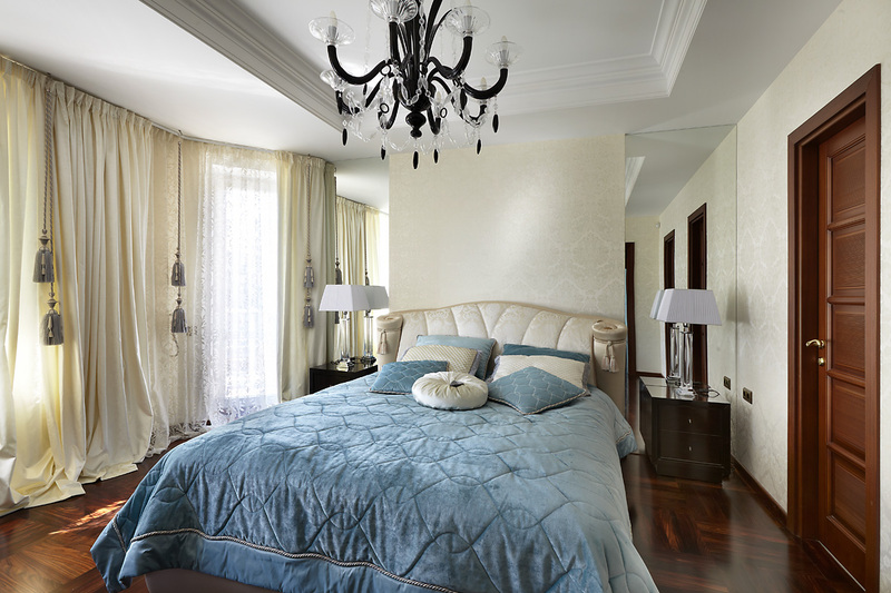спальня неправильной формы с кроватью и голубым покрывалом